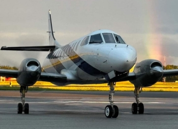 SkyCare Metroliner aircraft on the apron with a rainbow in the background